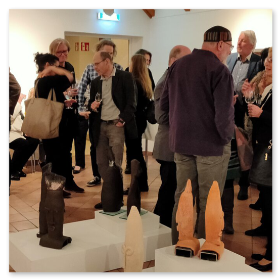 Ausstellung im Kunsthaus in Weiz. Skulpturen, Masken und Köpfe aus Keramik und Masken aus Glas. Gäste bei der Vernisage.